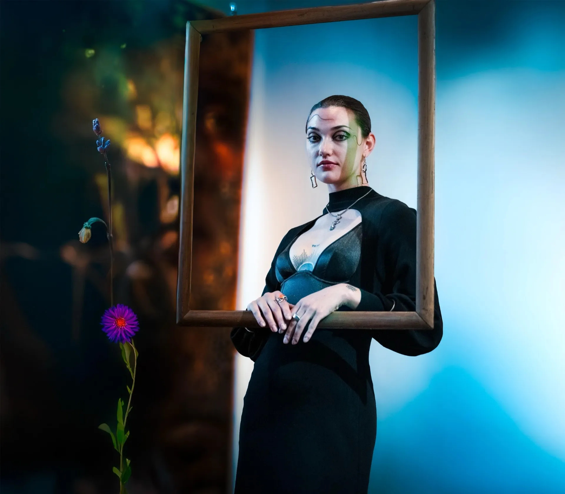 Girl holding a picture frame with flowers in the background, showcasing creative photography style